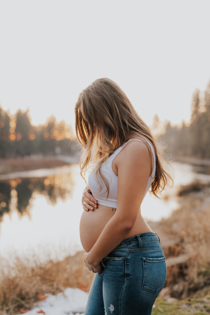 Profile shot of woman with bump showing, looking down at her bump.
